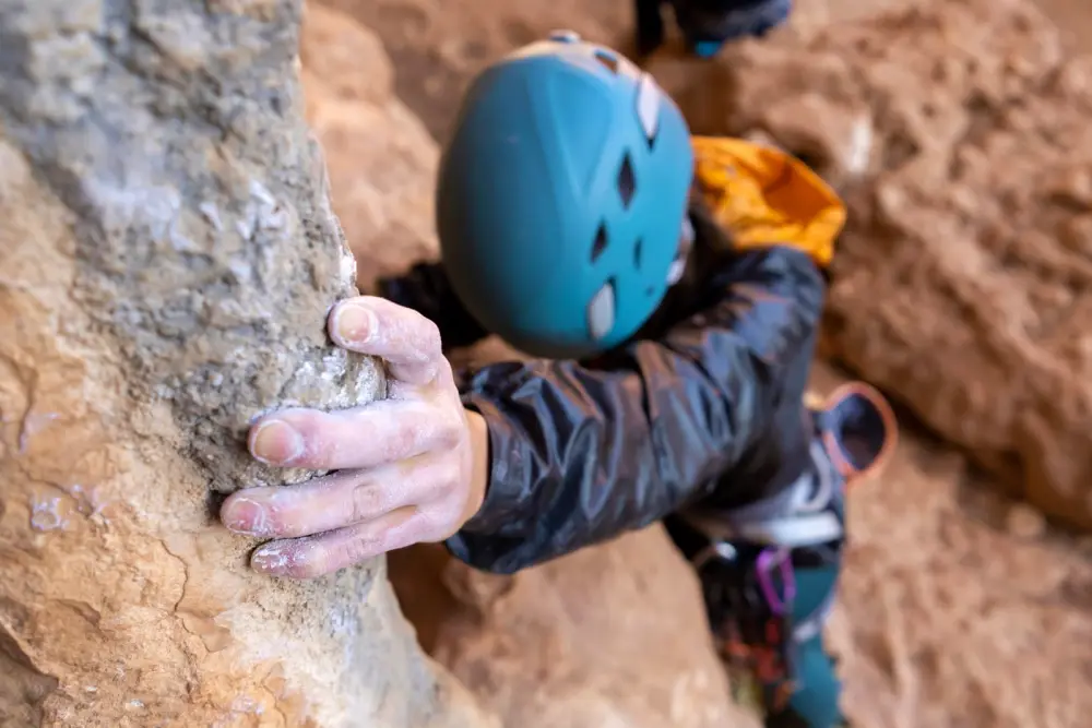 Young girl is engaged in mountain climbing, fearlessly climbs up the rock cliff.