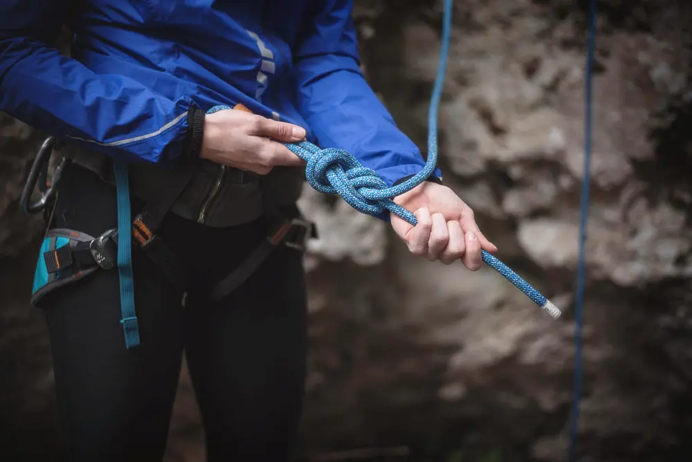 A woman preparing for rock climbing using her knot tying skills. 